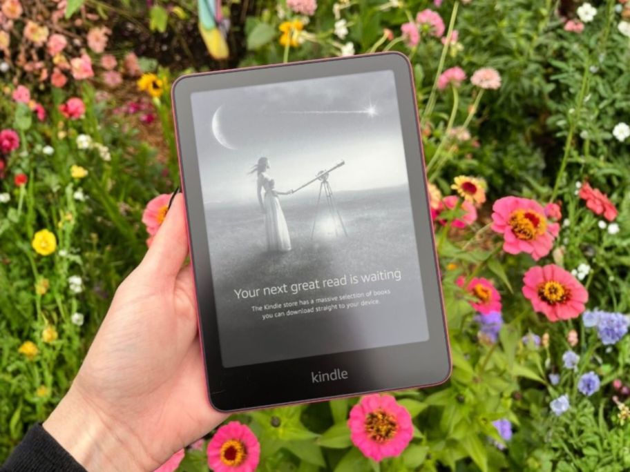 hand holding amazon Kindle Paperwhite 16GB in front of flowers