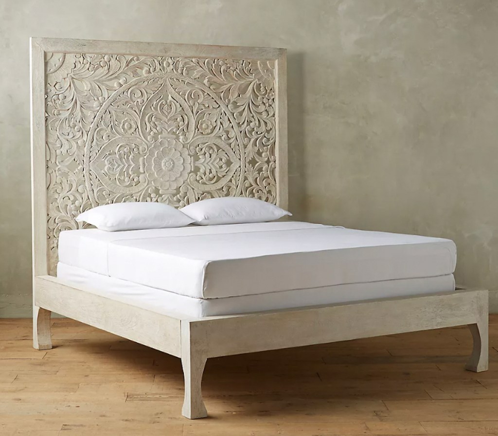 hand carved beige colored bed on wood floor 