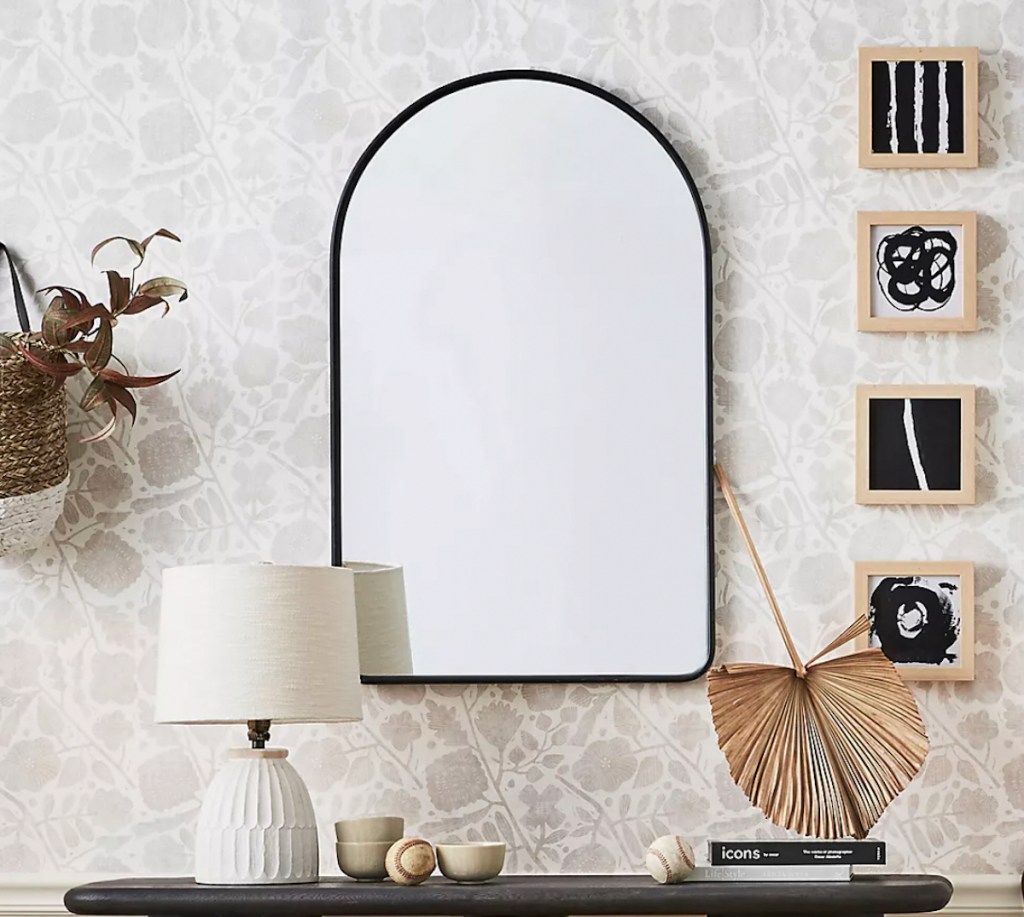 black arch mirror on floral wallpaper wall 