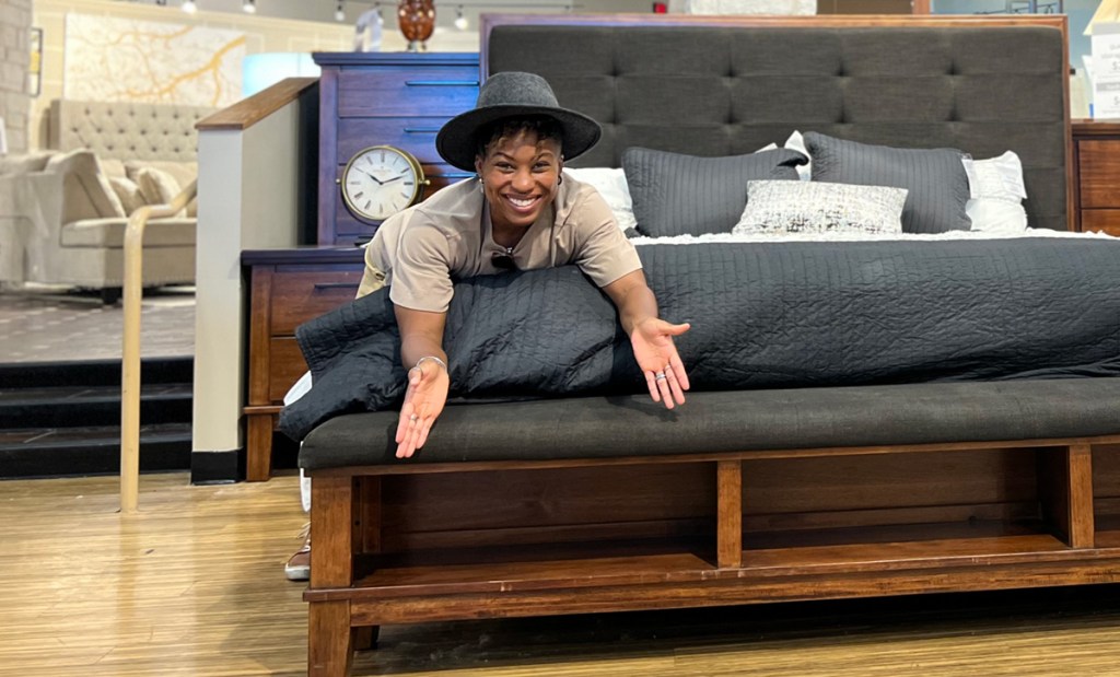women showing storage space in storage bed at ashley furniture