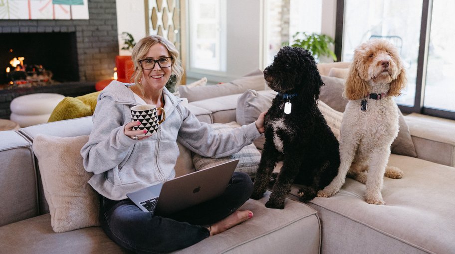 woman sitting on couch with laptop and two dogs 