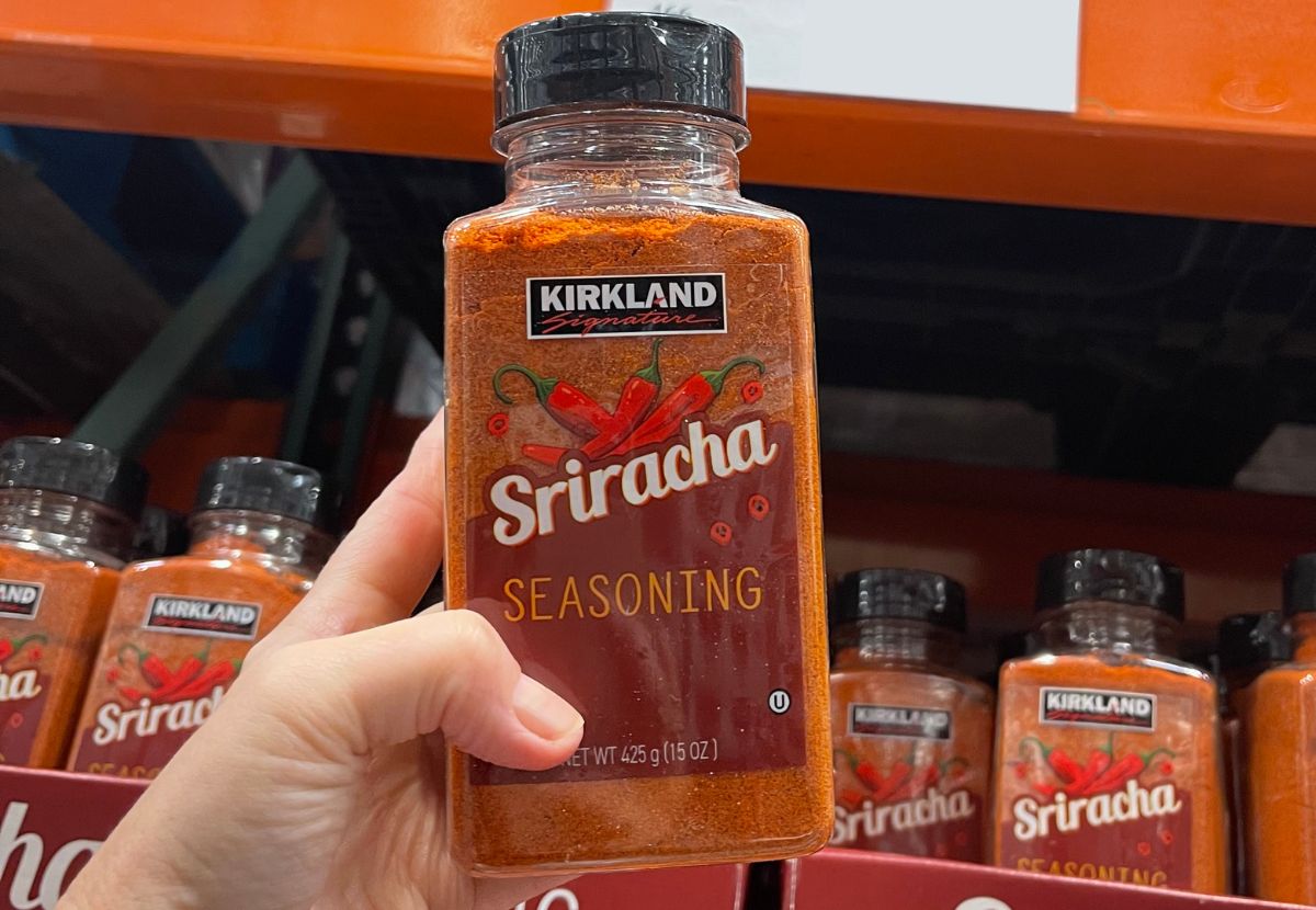 a hand holding a bottle of Kirkland's signature Sriracha seasoning