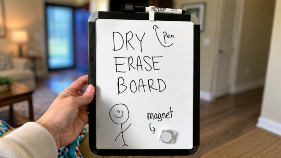 womans hand holding a dry erase board