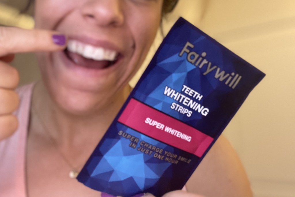 holding whitening strips pointing to teeth