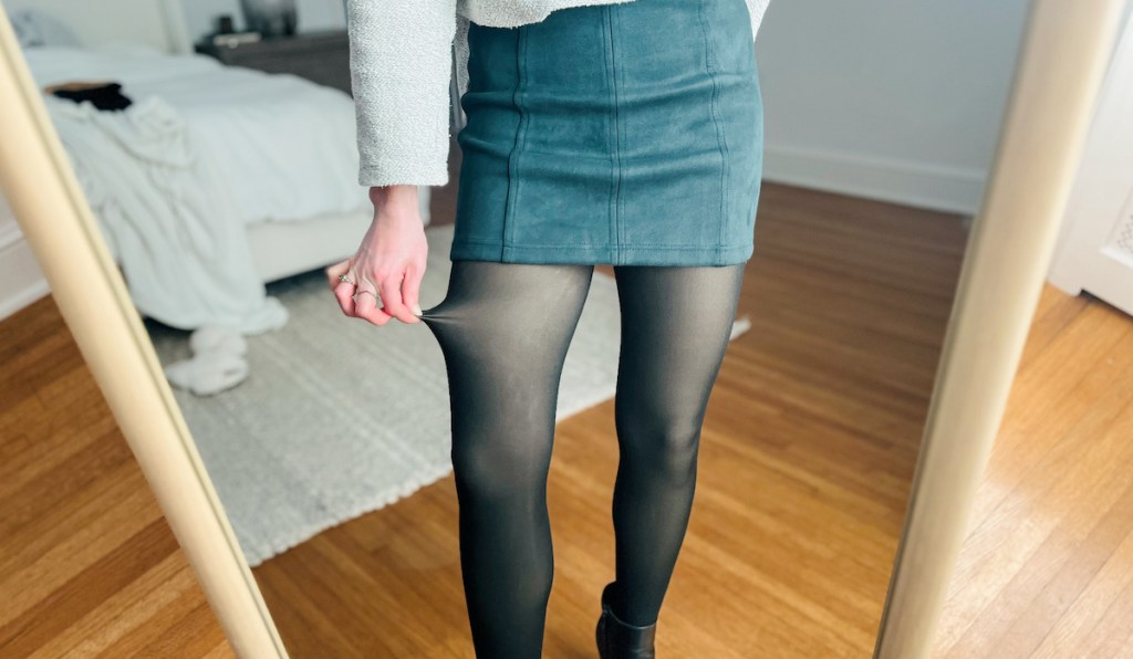 woman pulling side of fleece lined tights in mirror