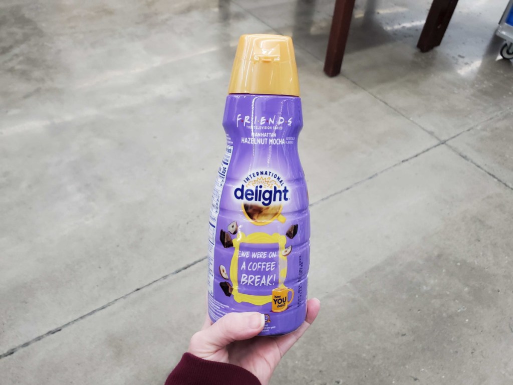 hand holding a bottle of friends international delight coffee creamer in store