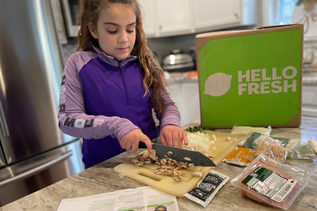 girl cutting food with hello fresh box