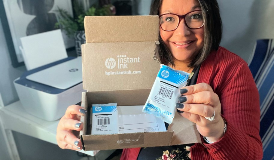 Woman holding up an HP Instant Ink box with ink refills.
