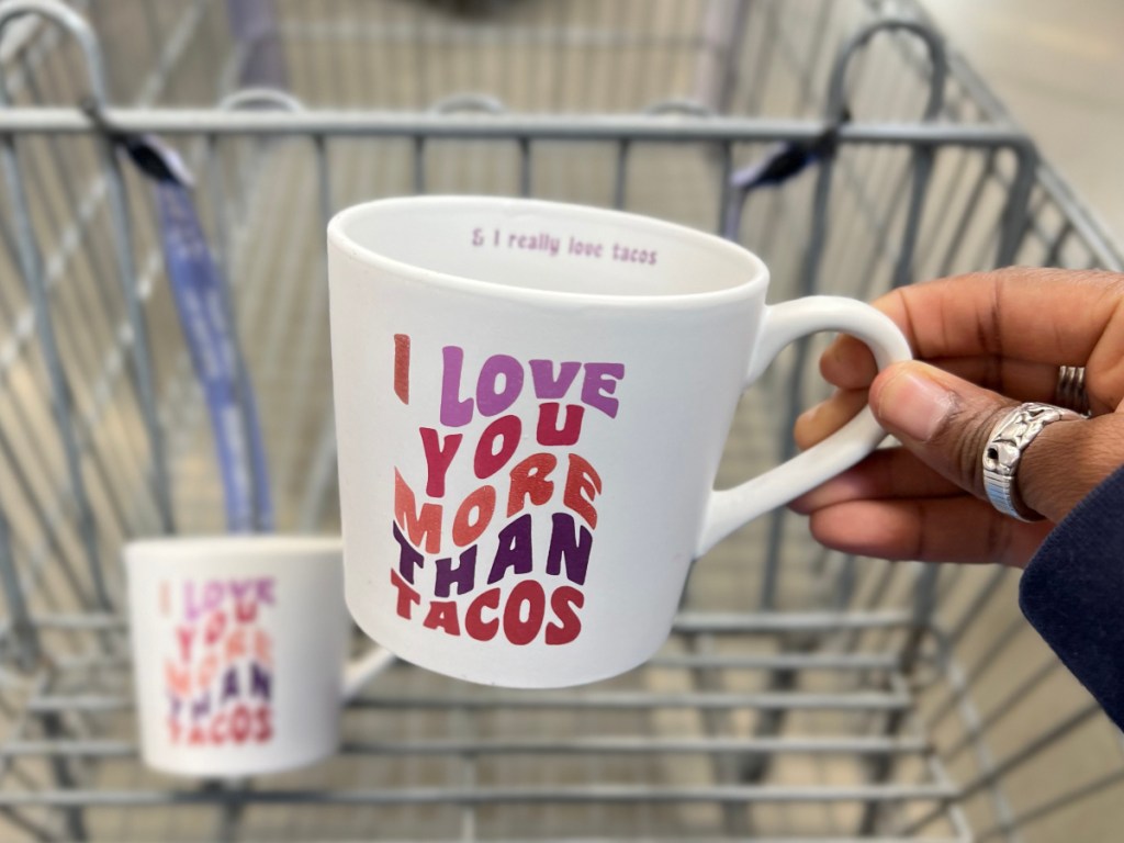 holding a white mug that says "I love you more than tacos"