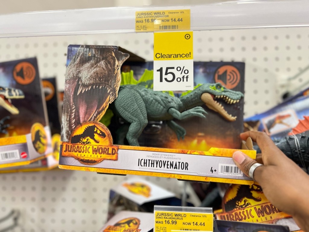 hoding a Jurassic World toy under a 15% off sign