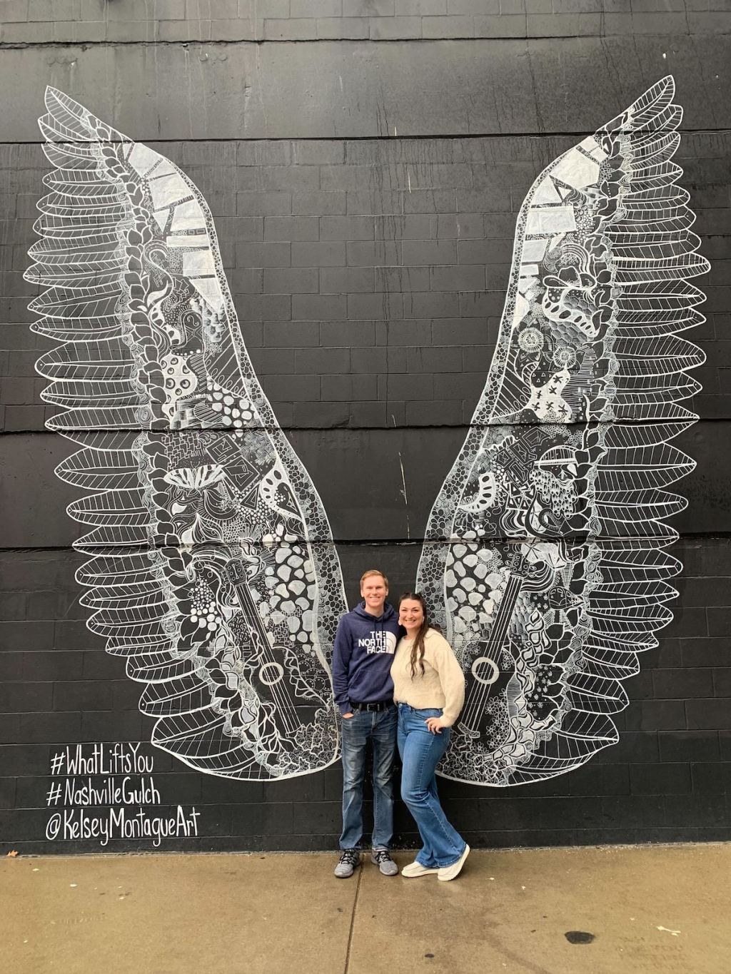 couple standing in front of nashville wings wall art 