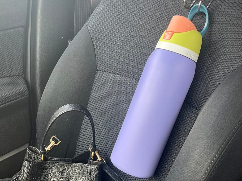 زجاجة ماء أرجوانية على مقعد سيارة رمادي