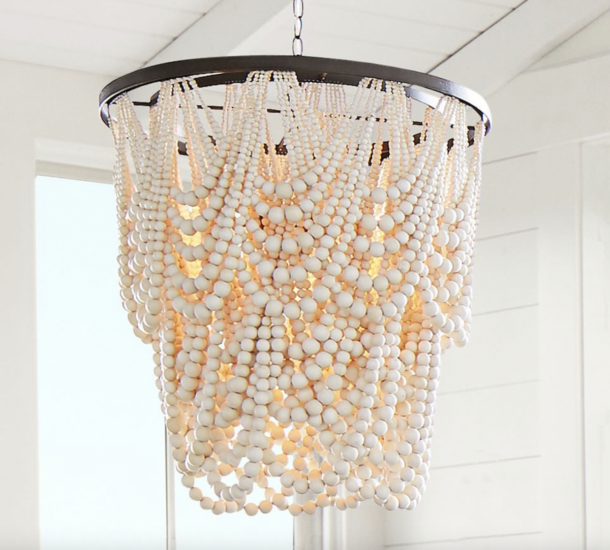 white wood bead garland chandelier lit up hanging from white ceiling