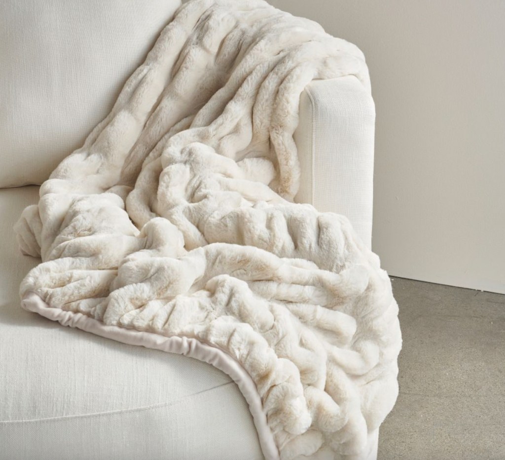 white faux fur blanket on cream accent chair 