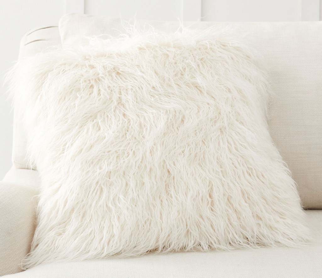 one white faux fur throw pillow on white couch 