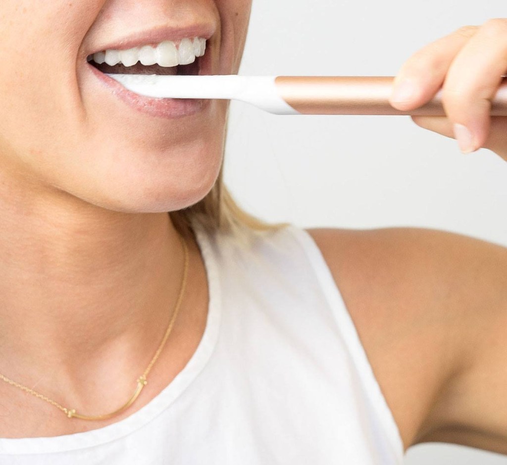 woman brushing teeth with pink toothbrush