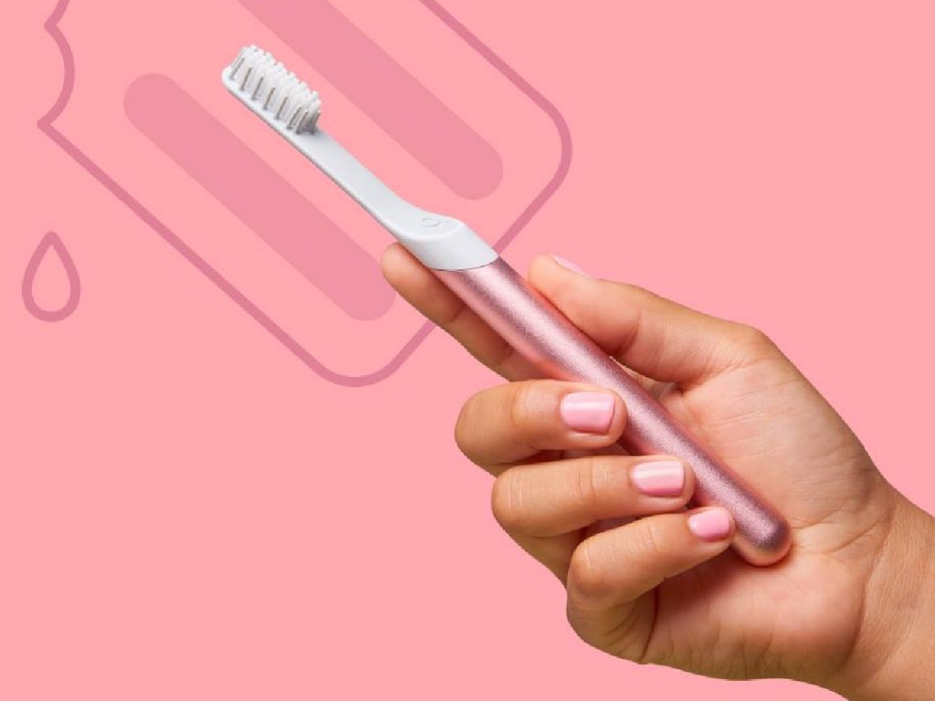 hand holding pink smart toothbrush