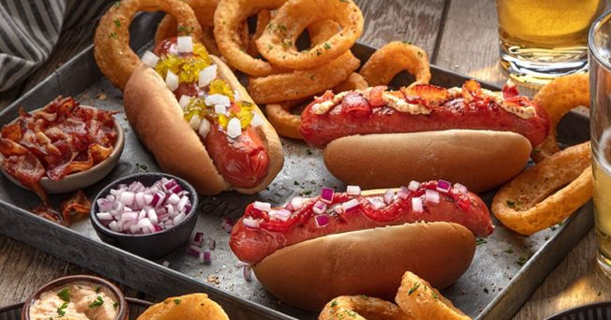 slaters 50/50 hot dogs on a tray with onion rings and toppings