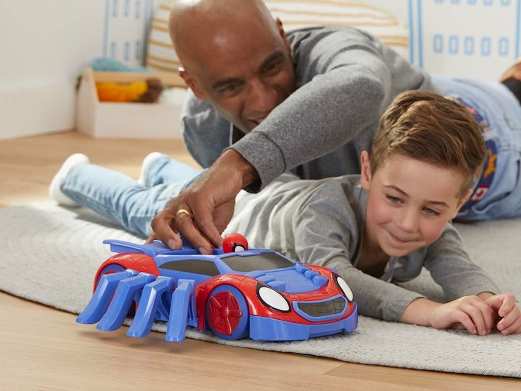 man and child playing with spiderman car