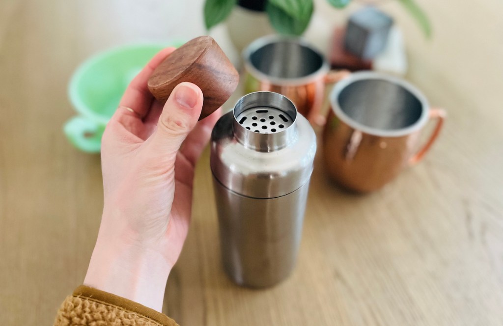 hand holding a wood cap from stainless steel cocktail shaker
