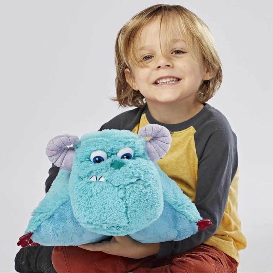 a little boy holding a sully monsters inc pillow pets