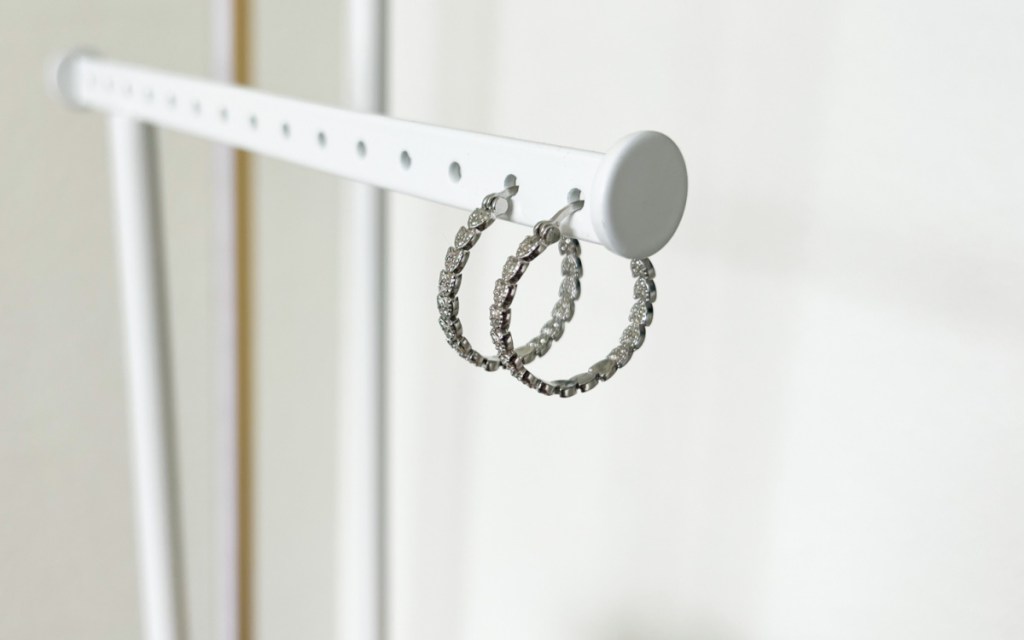 silver diamond earrings hanging on jewelery holder