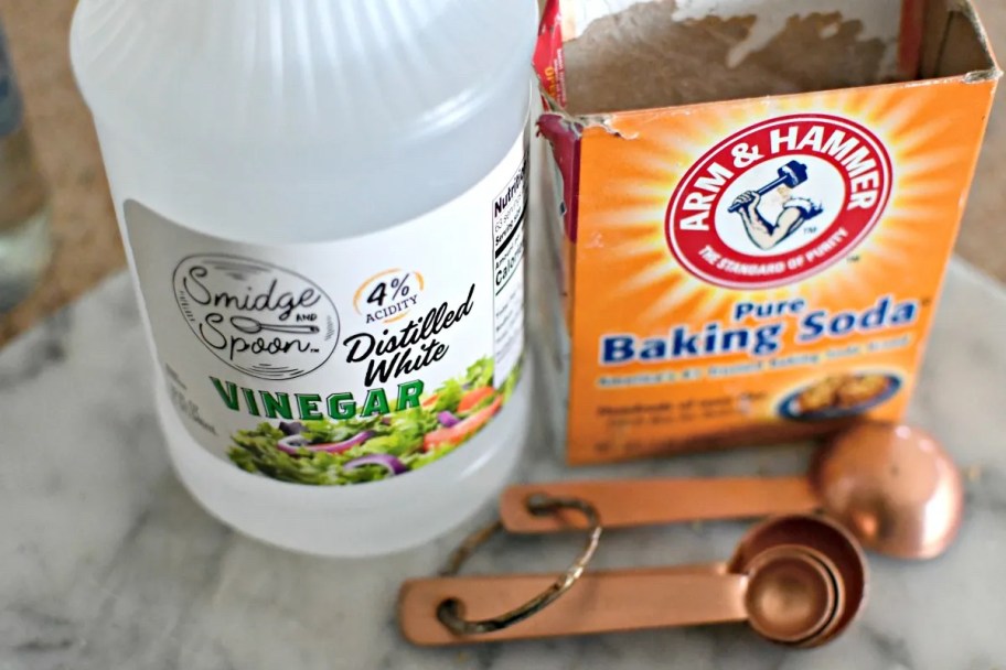 vinegar and baking soda on counter with rose gold measuring spoons