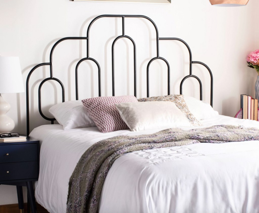 black iron bed with white bedding and throw pillows 