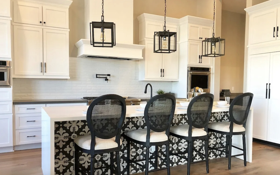 white kitchen cabinets with waterfall kitchen island and rattan barstools