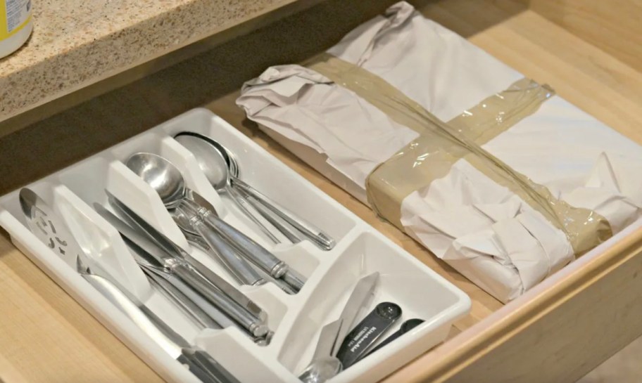 open drawer with silverware organizer and wrapped taped moving bin in drawer