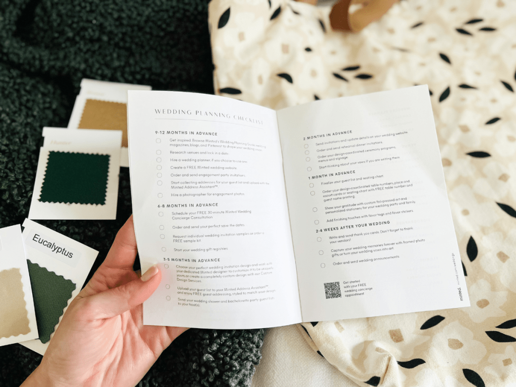 Minted Wedding Planning Journal shown with woman's hand and fabric swatches