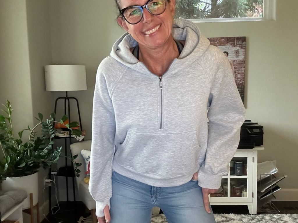 A woman wearing a gray pull over half zip sweatshirt