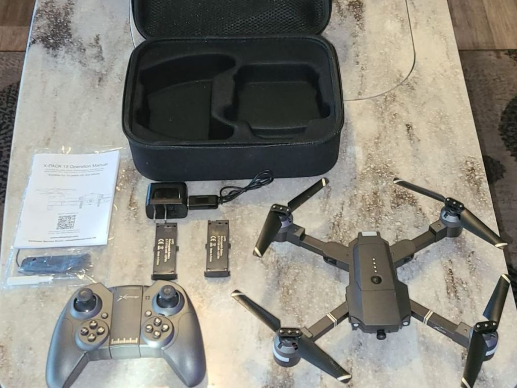 Aatop black drone laid out on a table with the remote, case, batteries and instructions