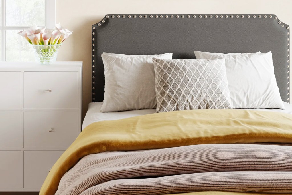 bed with grey headboard and yellow and pink blankets