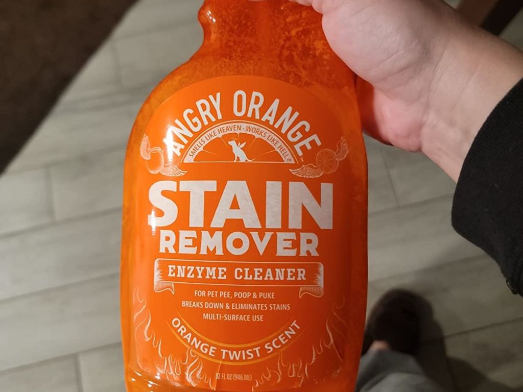 Hand holding a bottle of Angry Orange stain remover