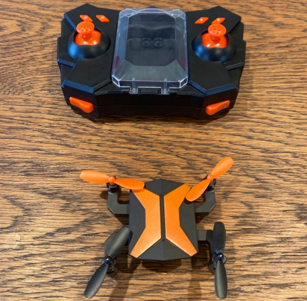 orange drone with controller on wood table