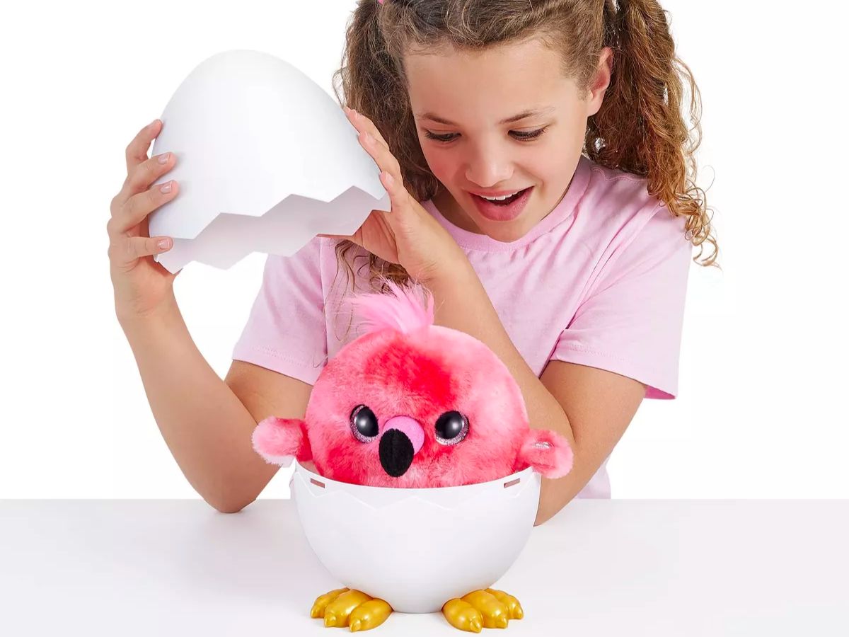 A little girl opening the white plastic egg to reveal her flamingo chirpy bird 