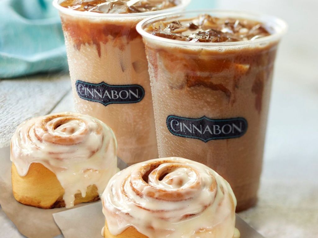 Two huge Cinnabon cinnamon rolls and two plastic cups filled with cold brew coffee drinks.