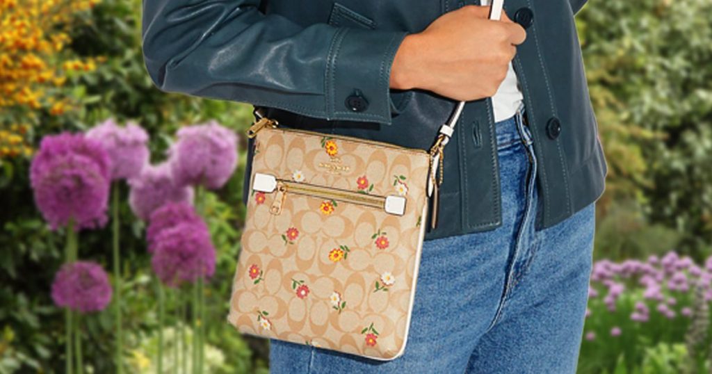 Coach Mini Rowan File Bag In Signature Canvas With Nostalgic Ditsy Print being worn by a woman in a garden