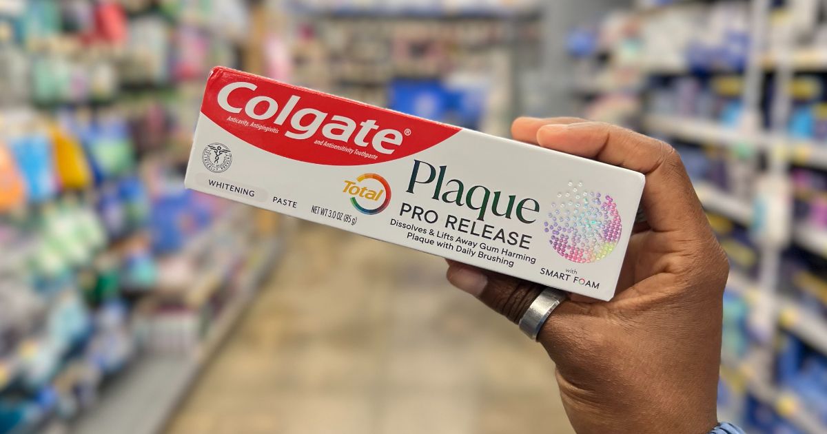 a womans hand holding a Colgate Total Plaque Pro Release Whitening Toothpaste
