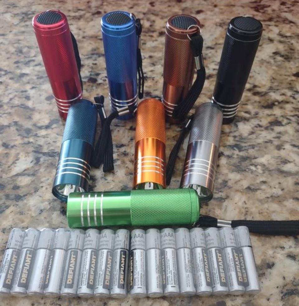 Group of flashlights and batteries sitting on a counter.