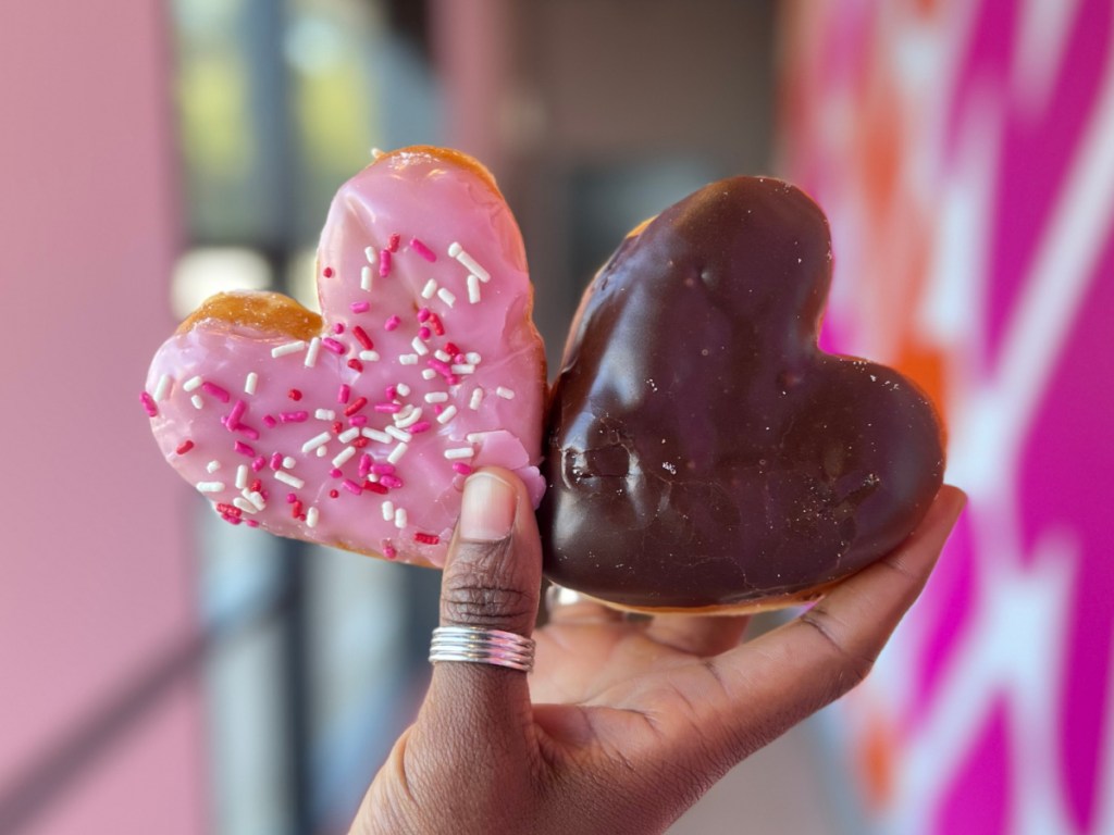person holding chocolate and pink colored heart shaped donuts