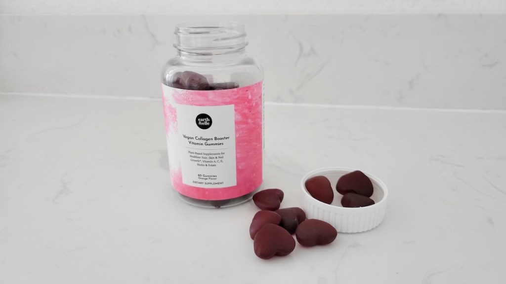 Bottle of Earth & Elle collagen booster with the lid open and gummies sitting next to the bottle