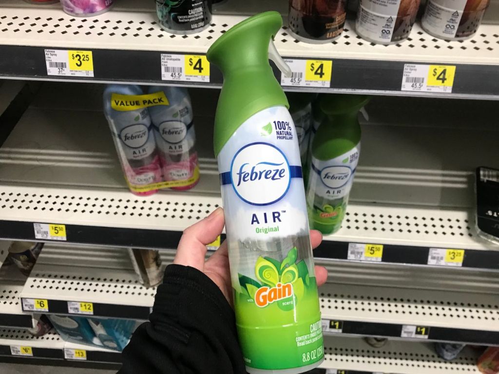 A bottle of Febreze air freshener held up by a woman's hand.