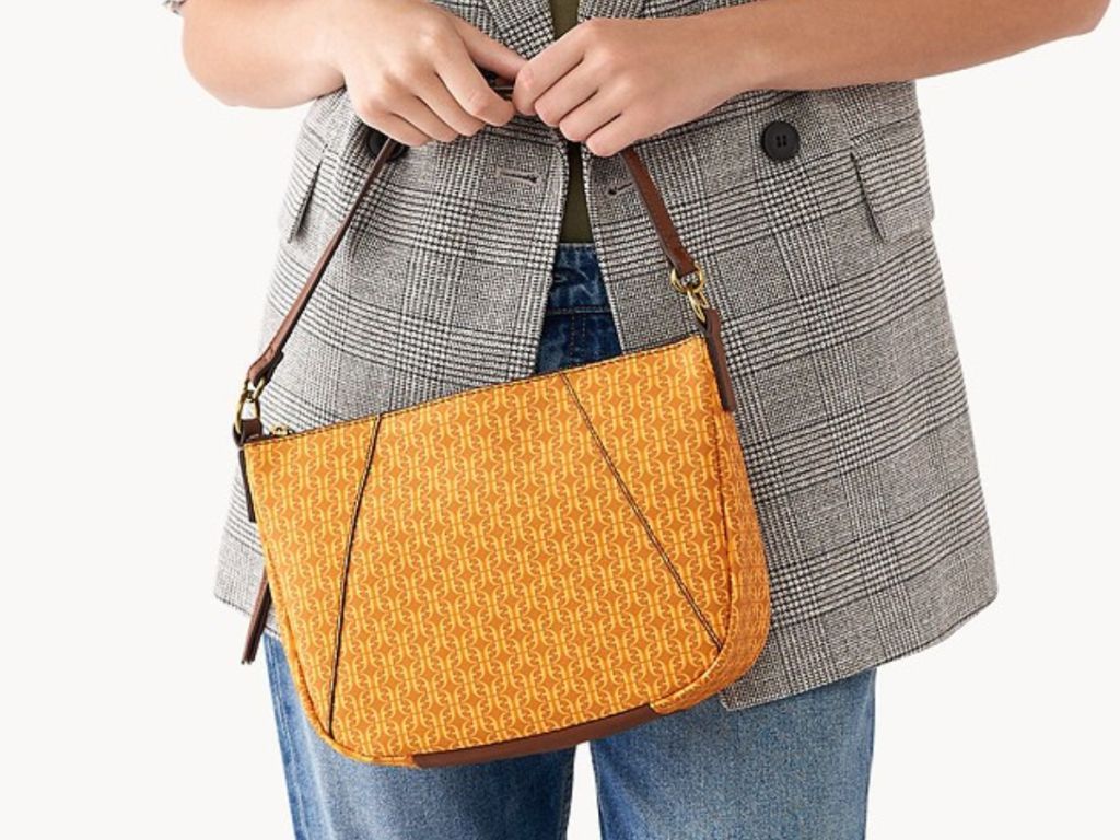 Woman holding a yellow and orange Fossil purse in front of her with both hands