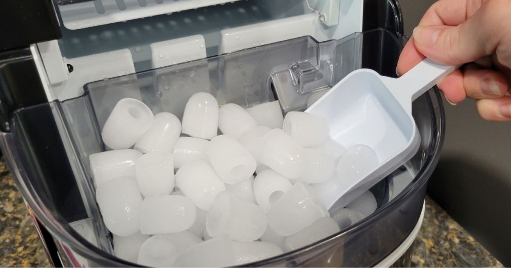 Free Village Ice Maker filled with bullet ice being scooped out with plastic scoop 