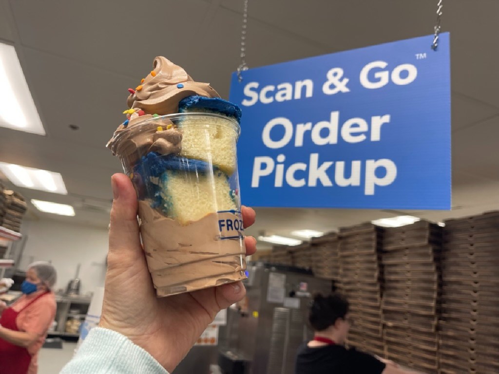 Hand holding up a frozen yogurt in front of the Scan and Go Order Pickup at Sam's Club