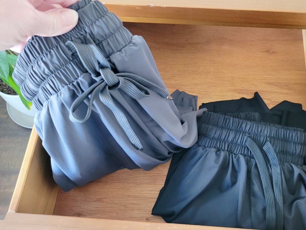woman taking out pair of gray running shorts from drawer