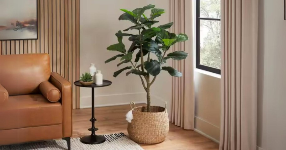 faux fiddle leaf fig tree in a tan woven basket by a window in a living room