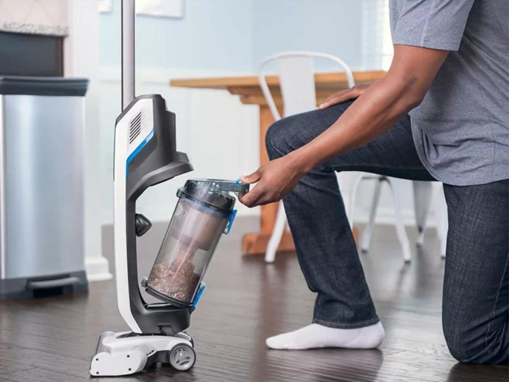 man bending to empty the canister on a HART cordless stick vacuum